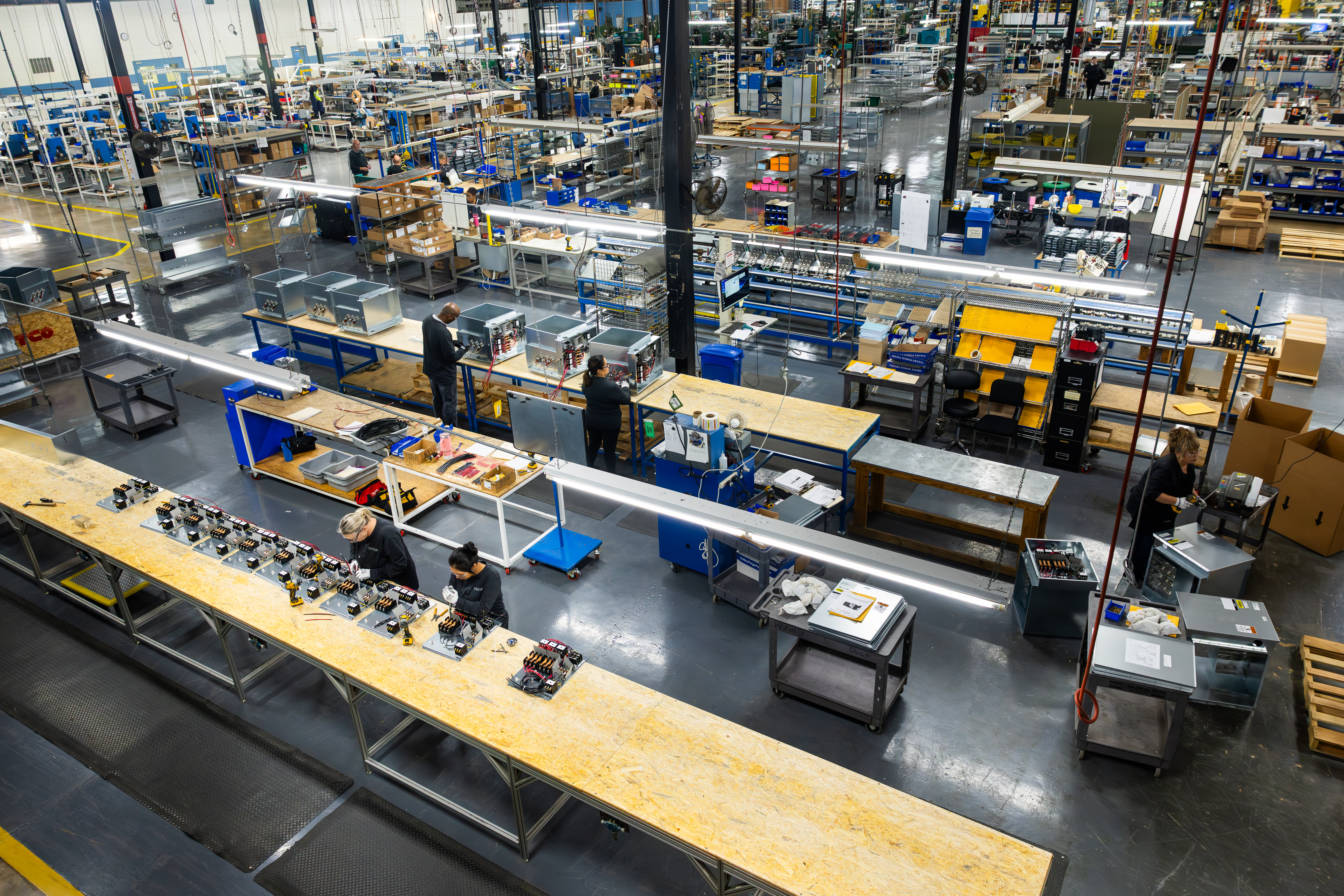 Tutco Employees Working In Factory At Long Desks