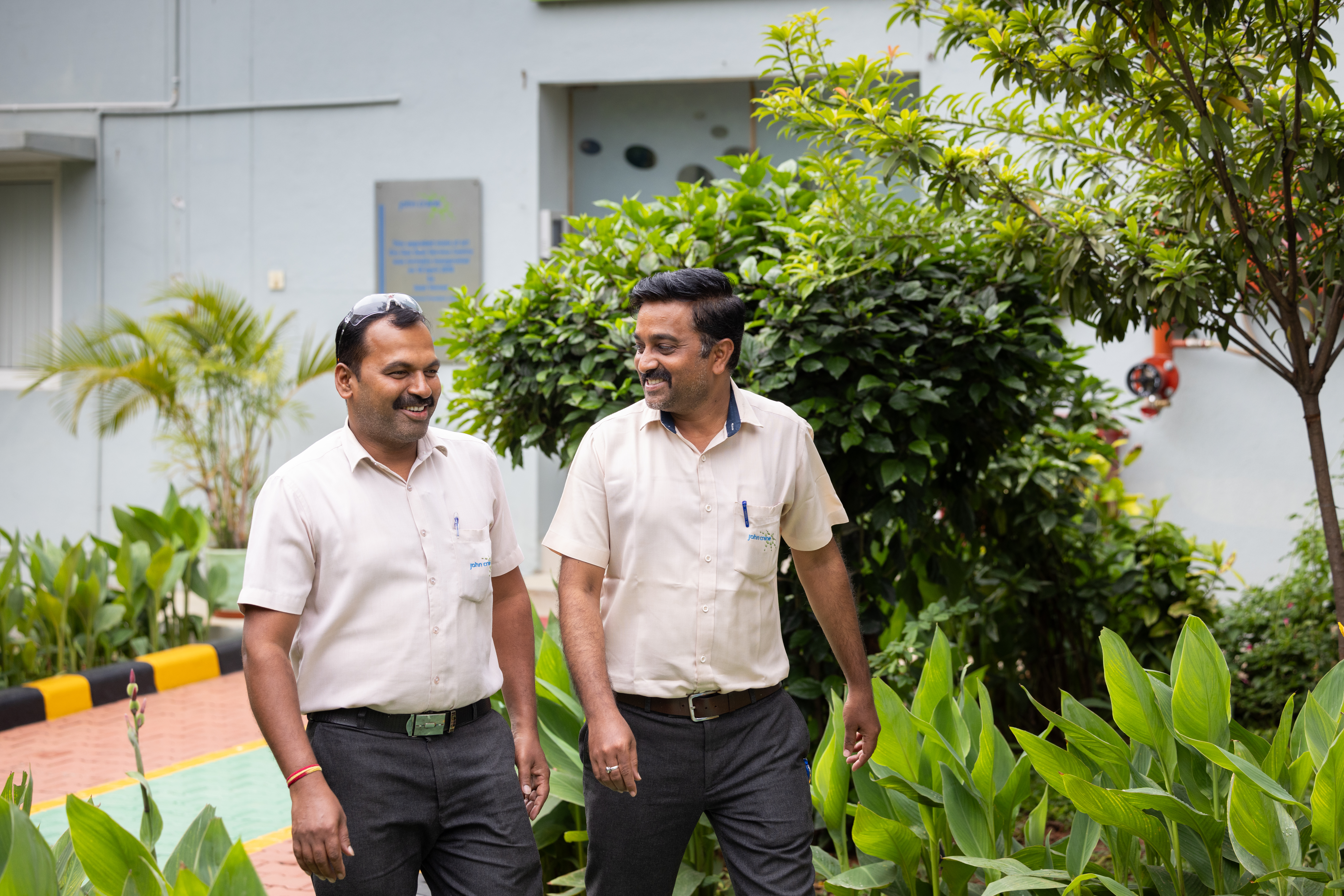 Two John Crane Workers Walking Outside Surrounded By Trees