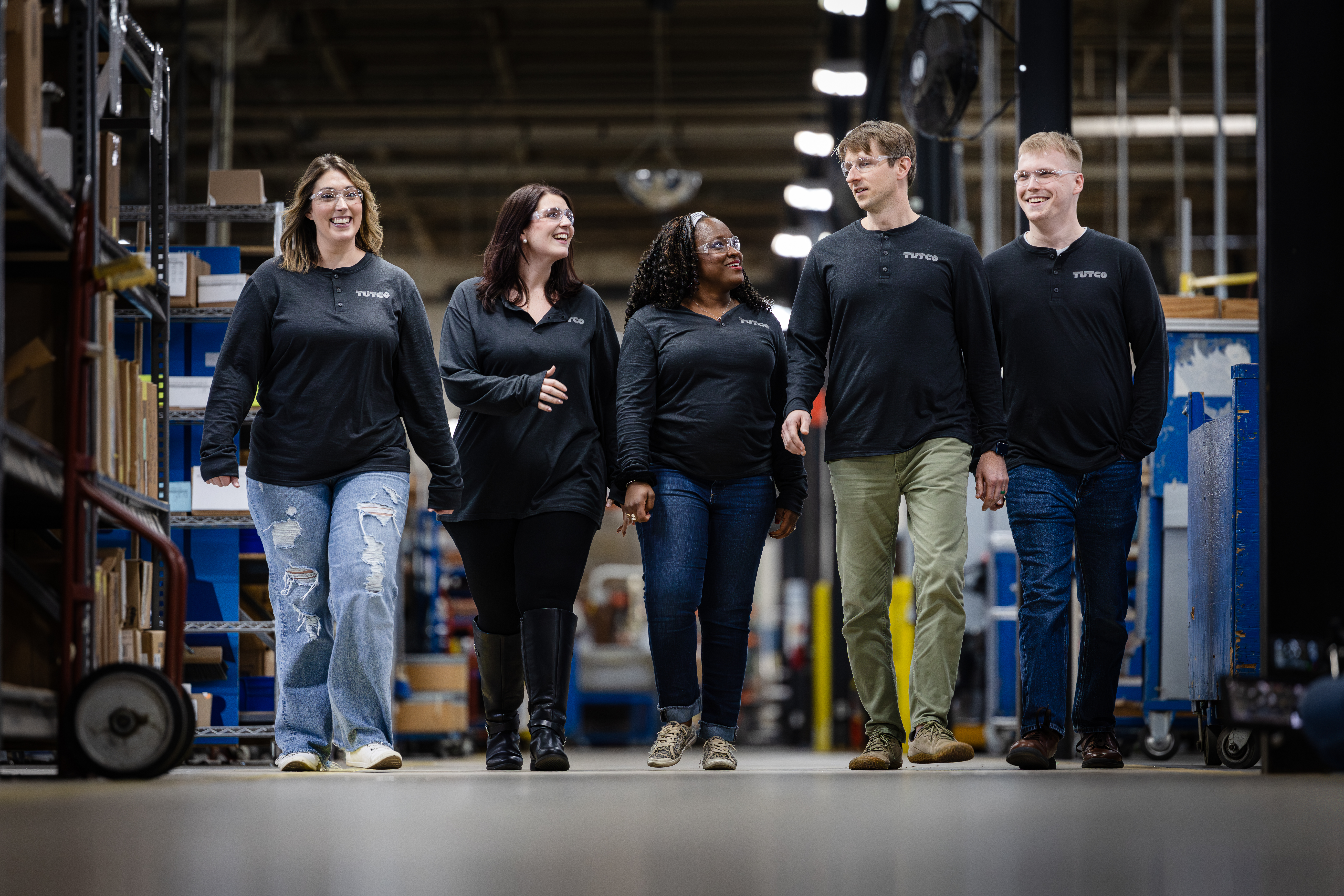 Five Workers In Tutco Uniforms Walking In Warehouse