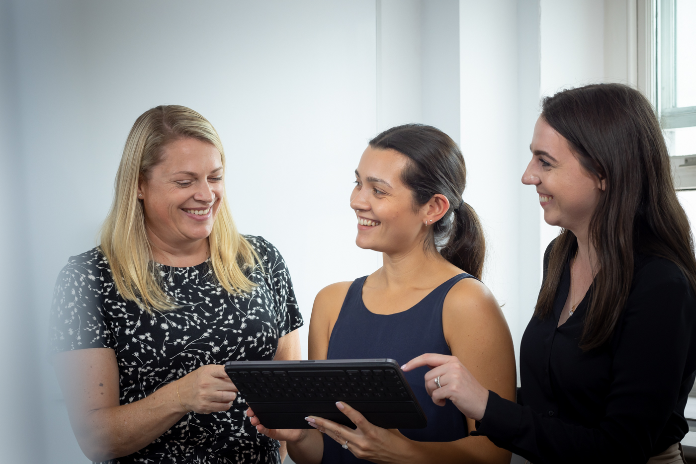Three Women Employees Looking At Tablet