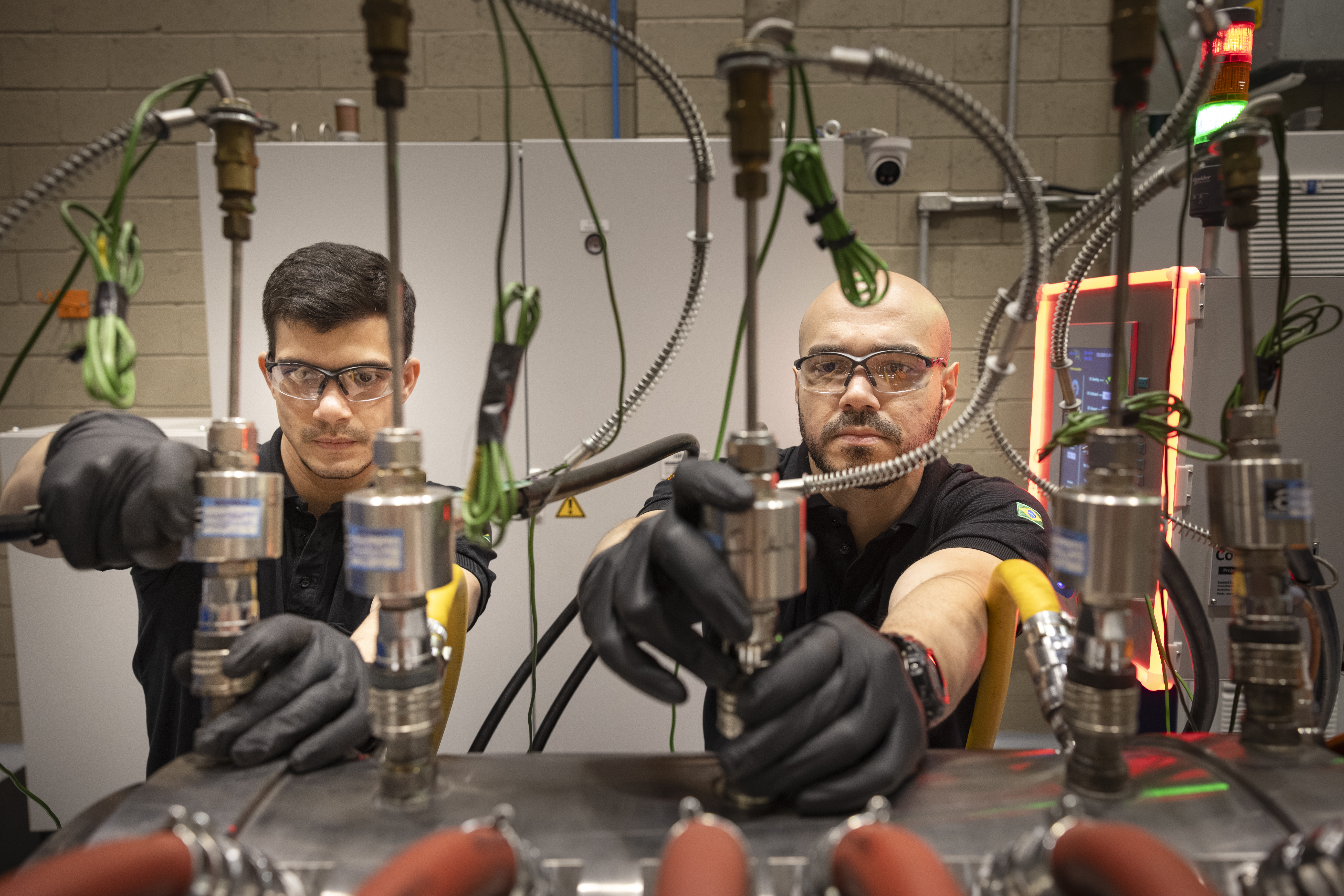 Two Men Working Wearing Safety Glasses And Black Gloves