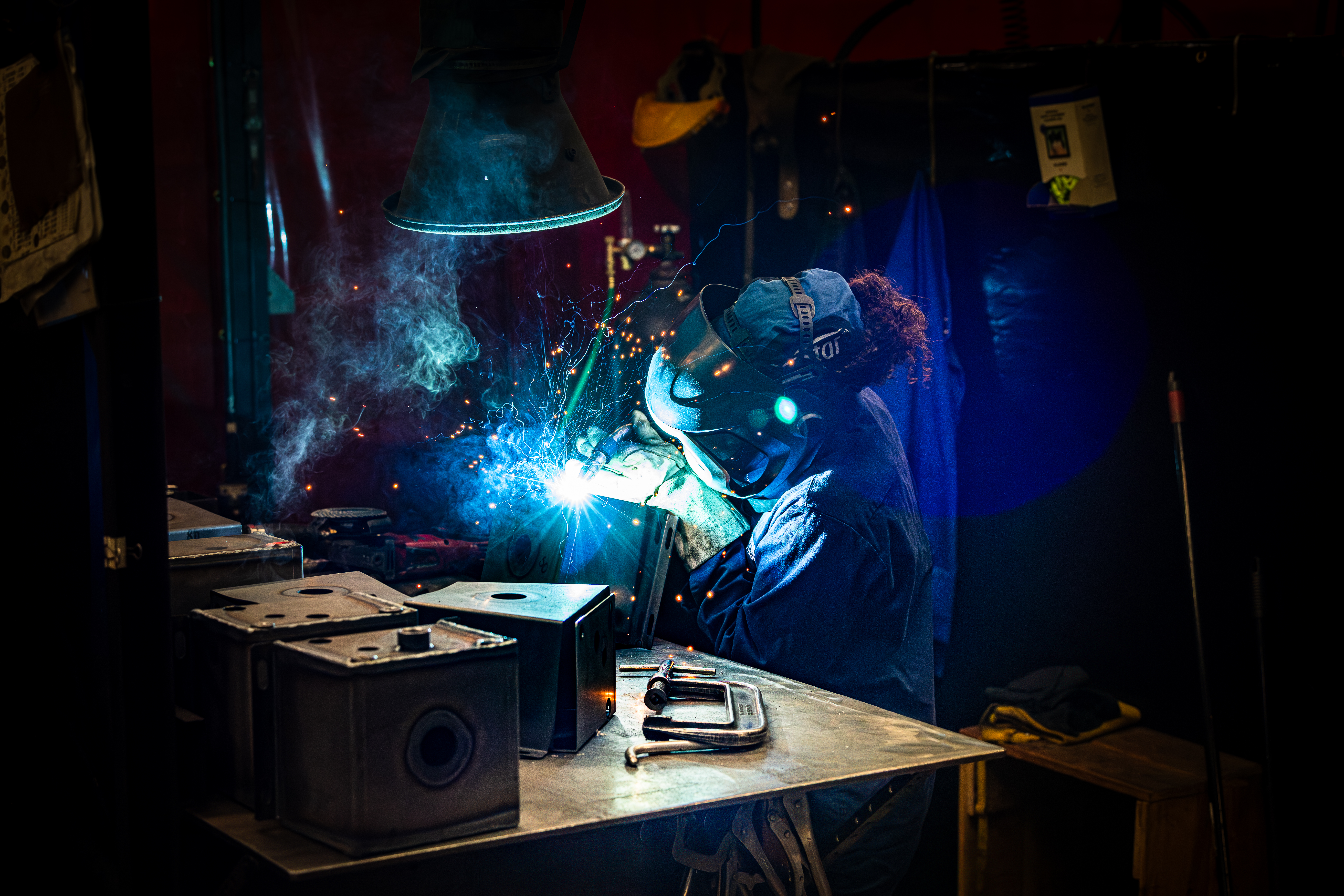 Welder Wearing Protective Clothes At A Workbench